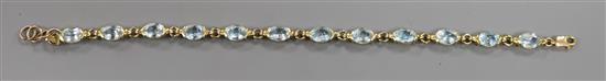 A modern 585 yellow metal and blue topaz set bracelet, 20cm.